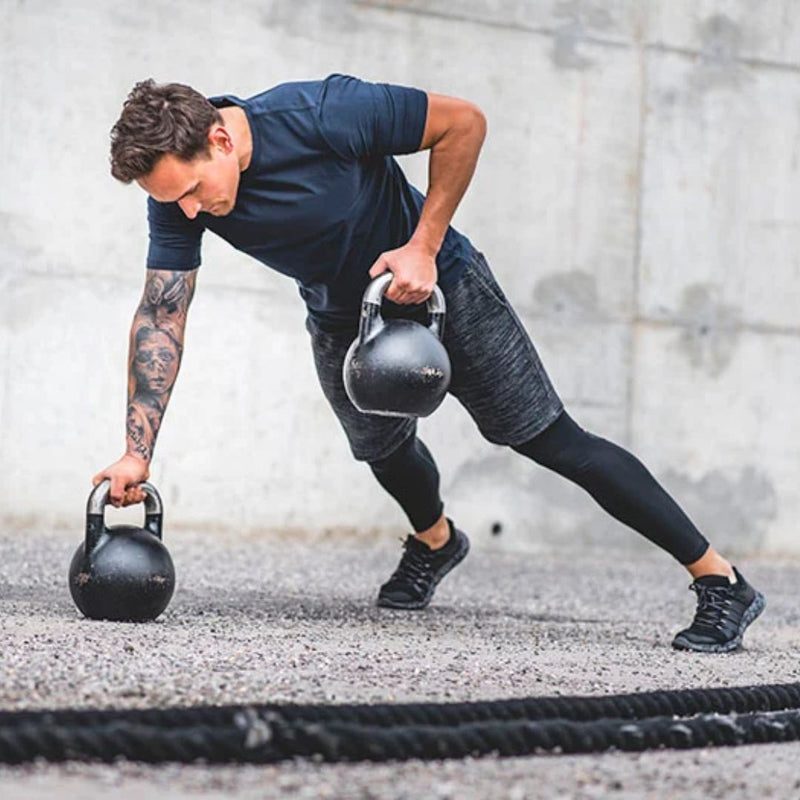 Man lifting kettlebells outdoors on a concrete surface