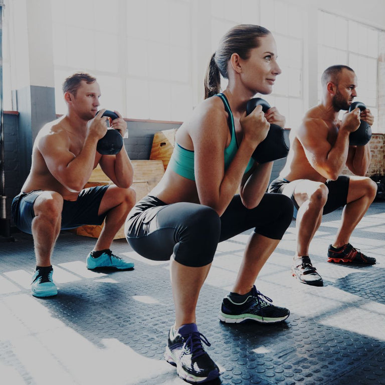 Three people performing squats in a gym setting