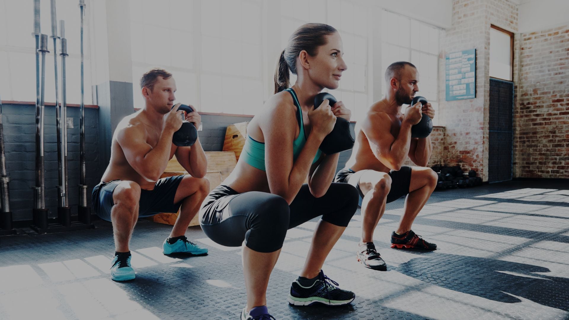 Three people performing squats in a gym setting